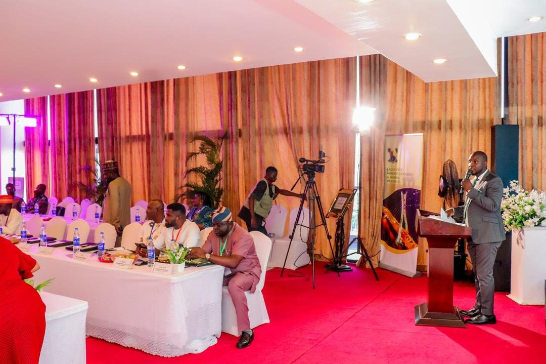 Abayomi speaking at a conference on a red carpet stage