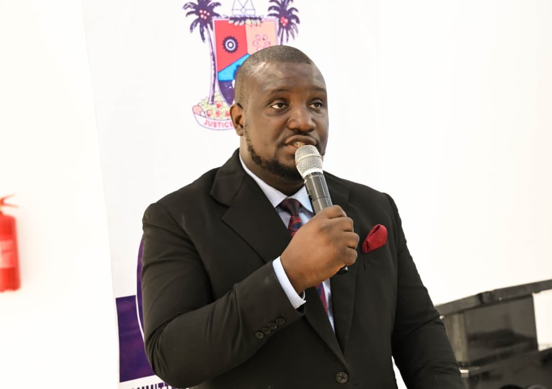 Abayomi speaking into a microphone in formal attire